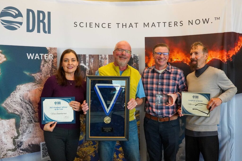 Four people holding up awards they have won.