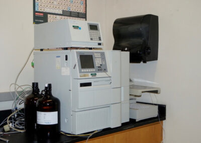A lab machine is sitting on the counter with cords and glass bottles.