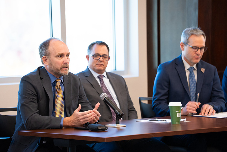 Sean McKenna speaking on a panel with two others with a microphone in front of him.